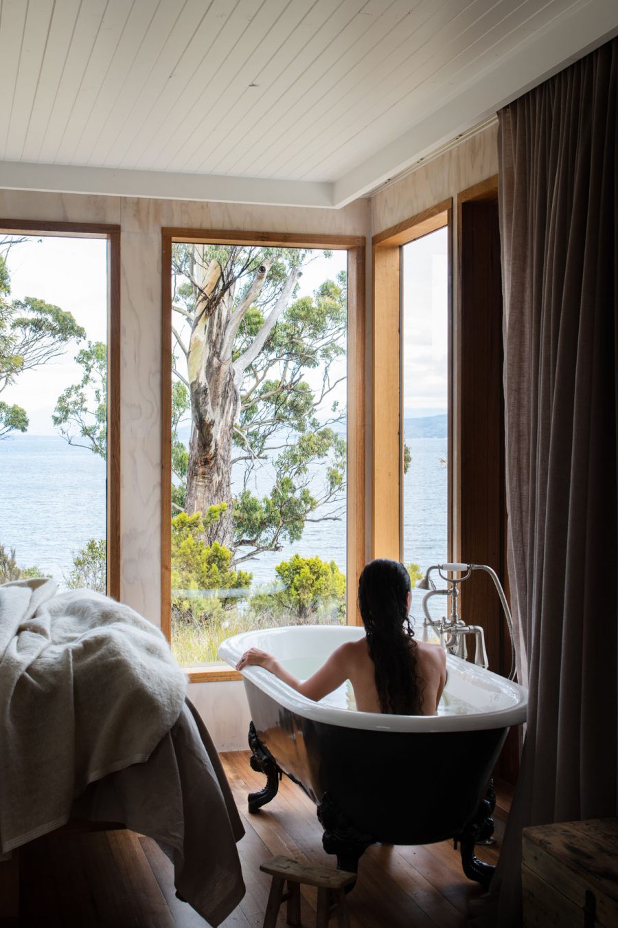 Woman in bath with view to Sheep Wash Bay - Tasmania