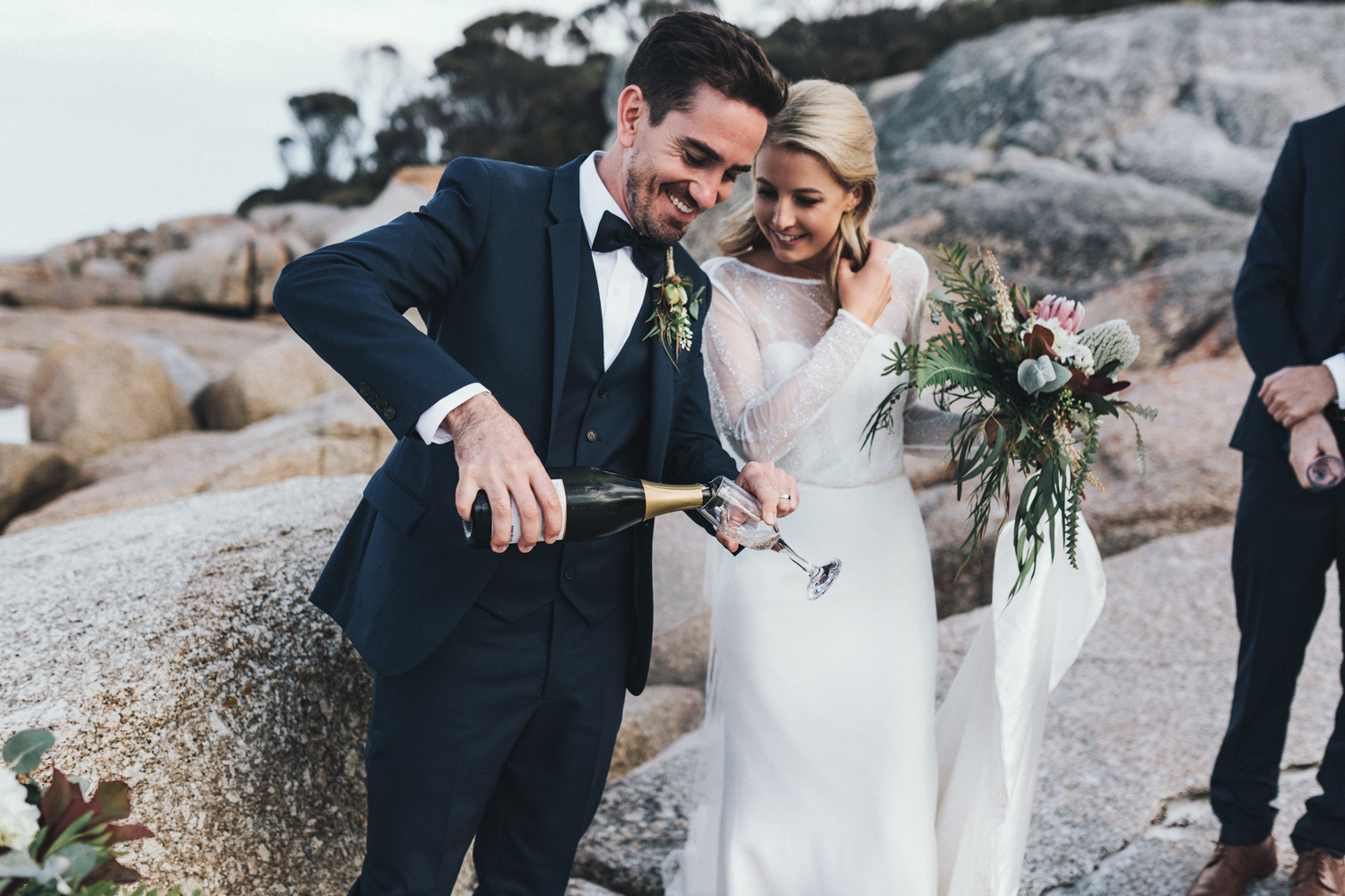 Groom pours champagne for his bride at Bay of Fires Tasmania.