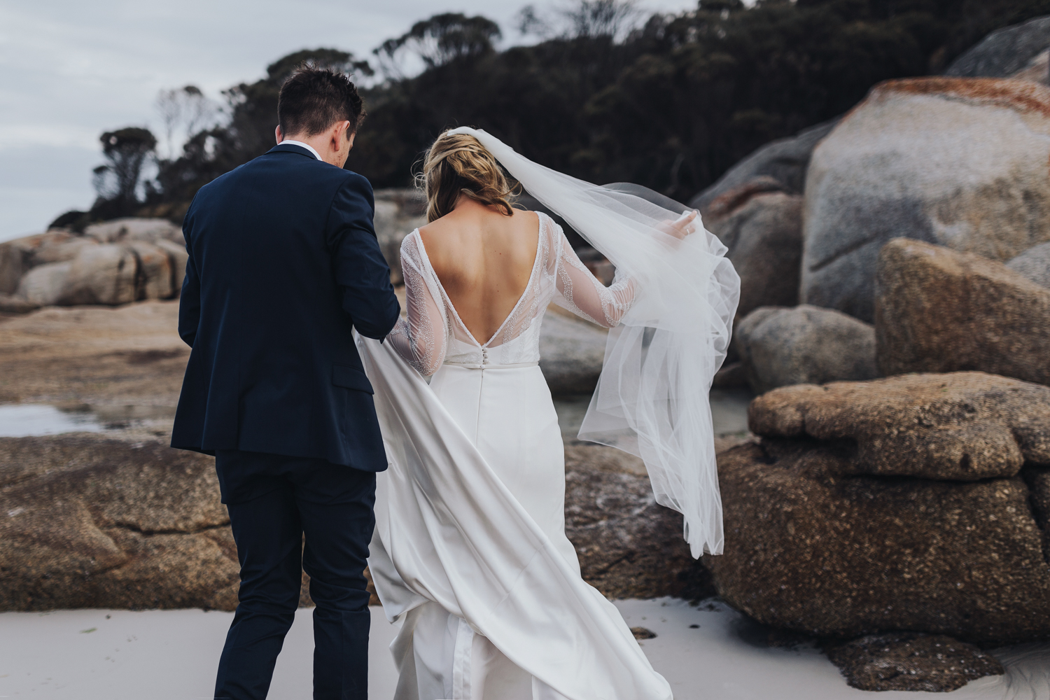 Bride and groom walk on beach at Bay of Fires wedding in Tasmania