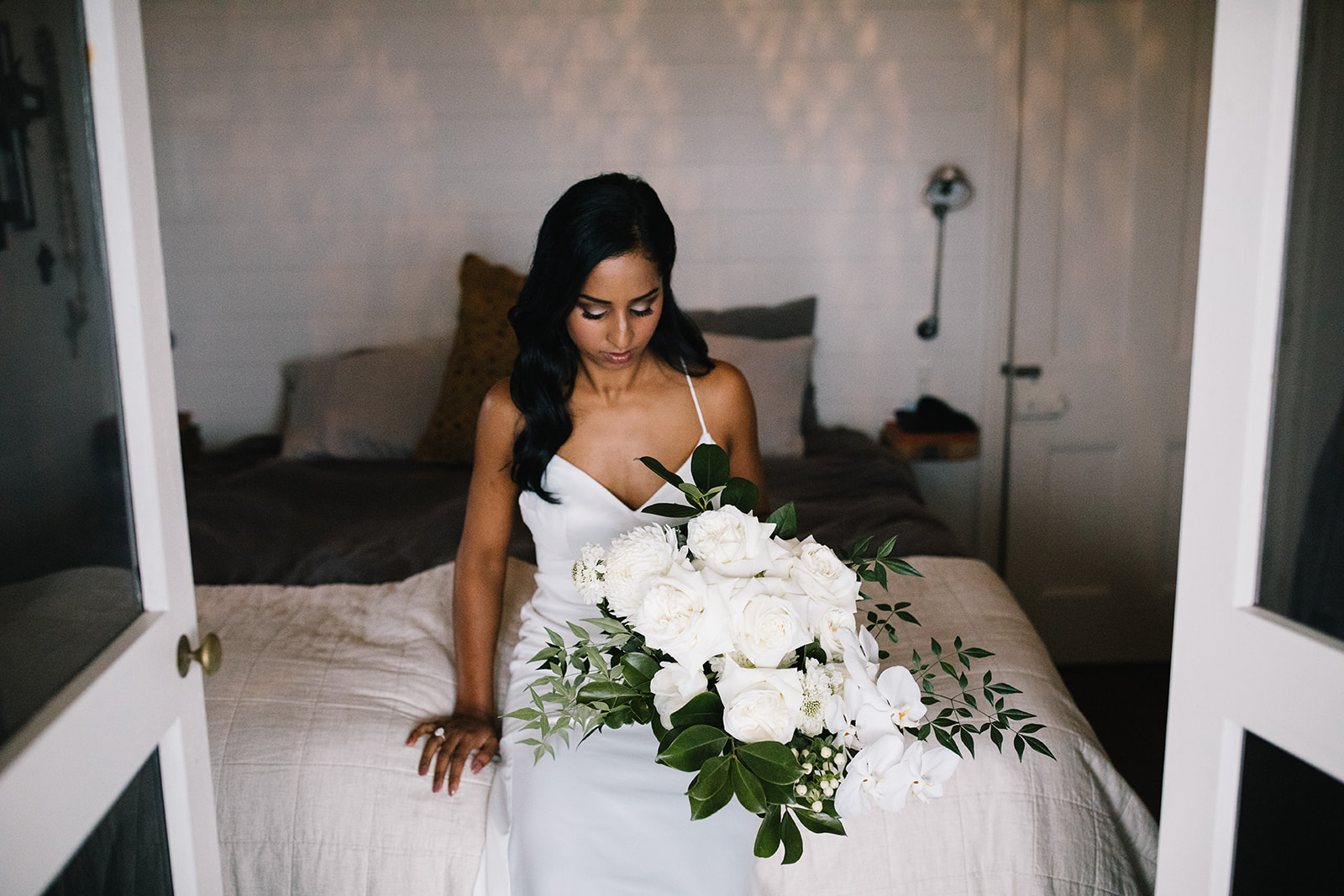Bride sitting on bed with flower bouquet / Wedding photography